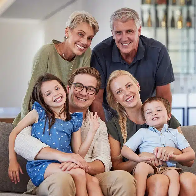 Happy multi-generational family smiling together indoors on couch
